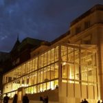 Illuminated building with glass extension at night.