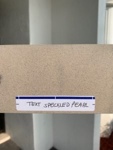 Speckled pearl textured surface sample with label.