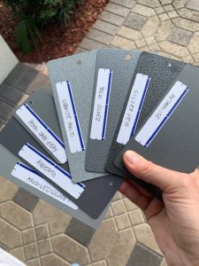 Hand holding gray color sample cards outdoors.