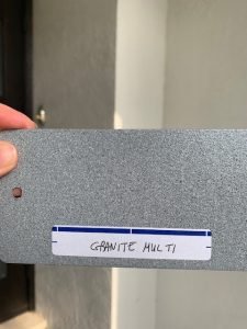 Hand holding gray granite color sample.