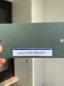 Weathered bronze colored panel held outside.
