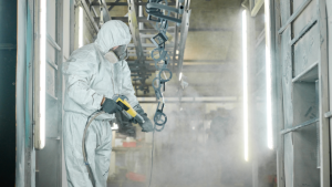 Worker sprays paint in protective gear.