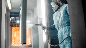 Worker spray painting metal in protective gear