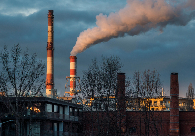 Industrial smokestacks releasing smoke into the sky.