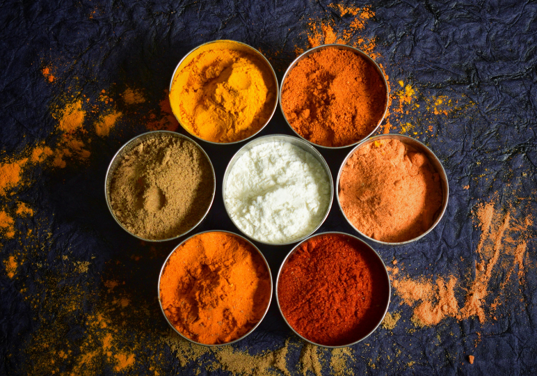Colorful spices arranged in circular pattern on cloth.